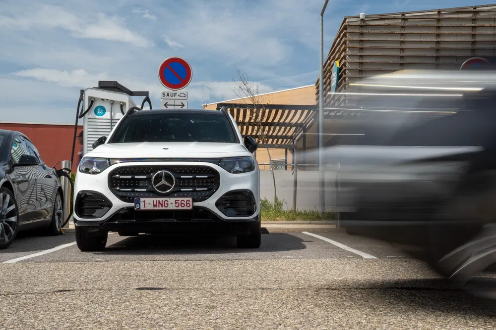 Mercedes-Benz électrique blanc en charge dans un parking urbain, voiture floue à droite.