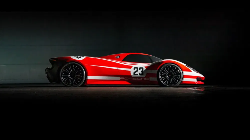 Voiture Porsche rouge et blanche avec le numéro 23 sur un fond sombre.