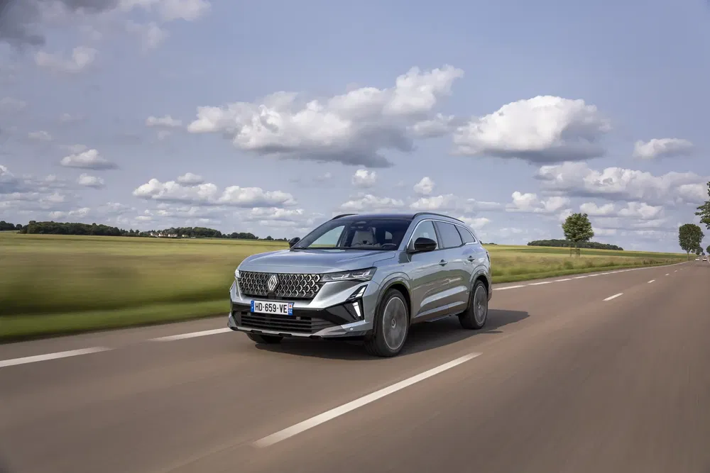 SUV MG traverse une route de campagne sous un ciel partiellement nuageux.