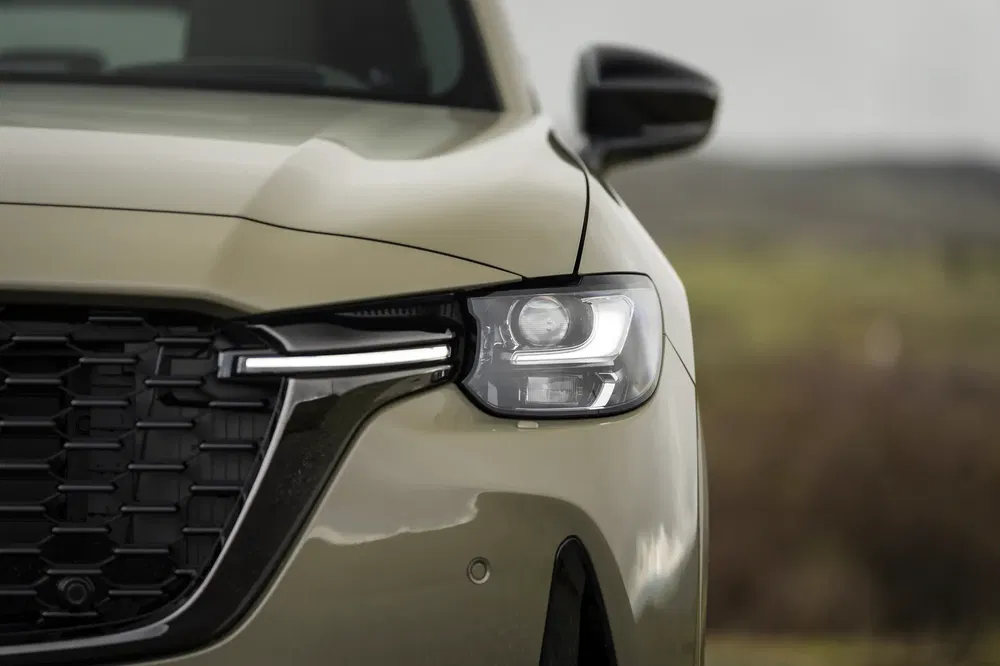 Gros plan de l'avant d'une Mazda CX-60 beige avec phare LED distinctif.