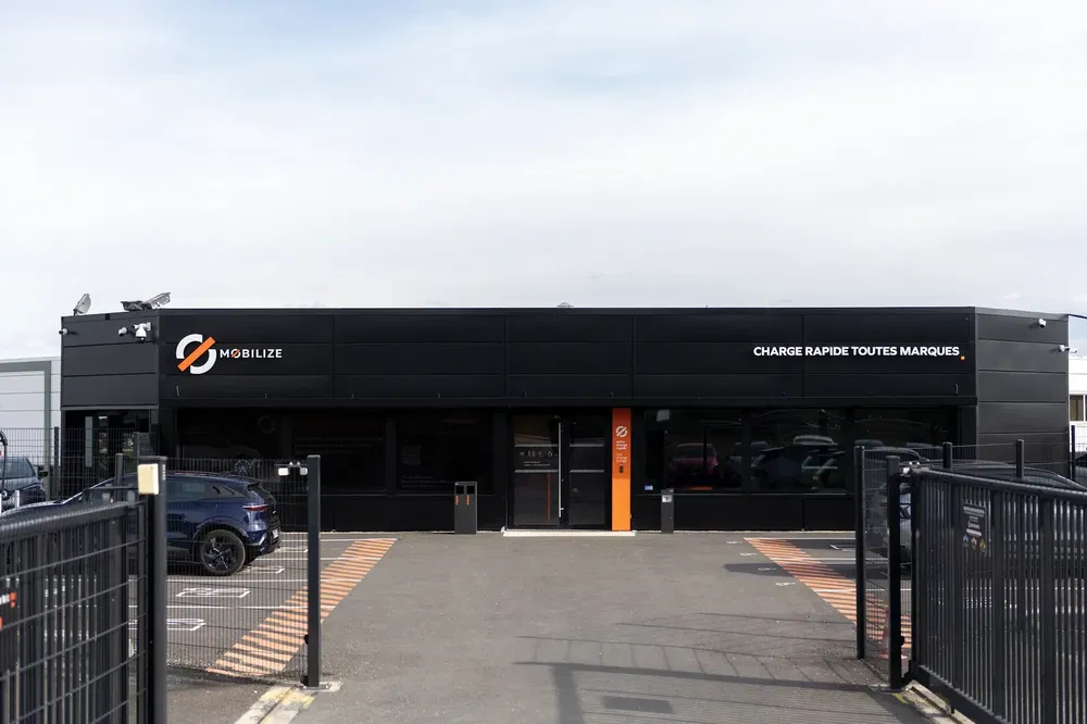 Station de recharge rapide Mobilize avec parking devant, ciel dégagé.