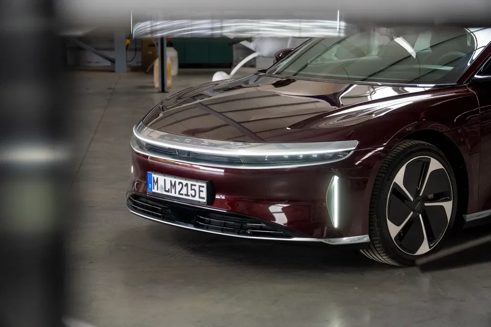 Lucid Air électrique brun dans un garage industriel, focus sur l'avant futuriste et les phares LED.