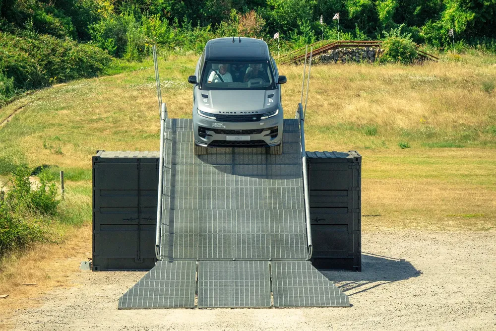 {"fr":"Le Range Rover descend une rampe métallique sur un terrain de campagne verdoyant.","nl":"De Range Rover rijdt een metalen helling af op een groen plattelandsterrein."}
