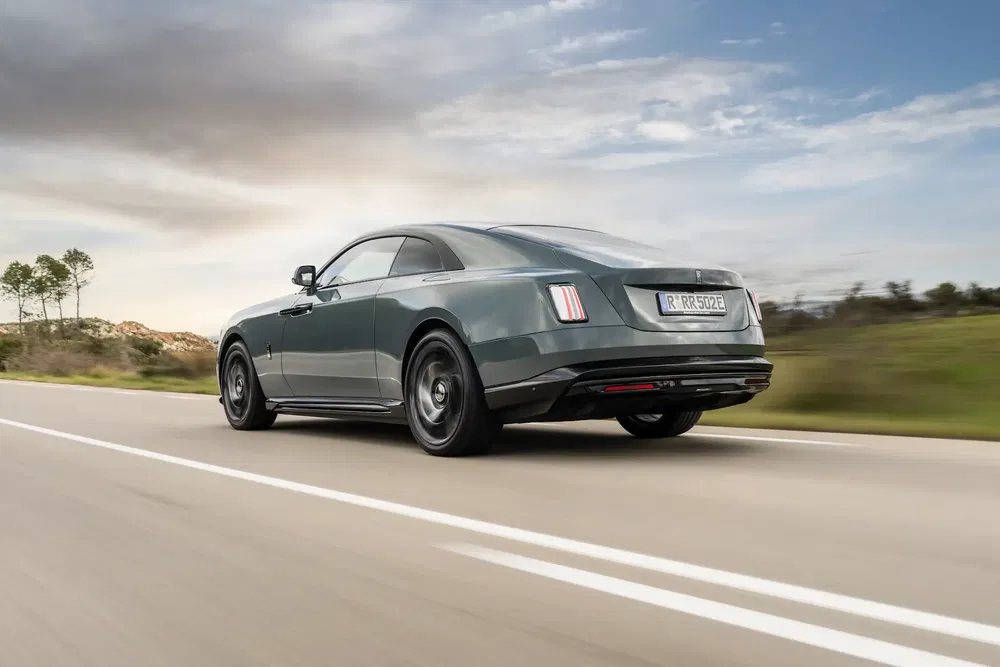 Rolls-Royce Spectre roulant sur une route dégagée, ciel nuageux en arrière-plan.