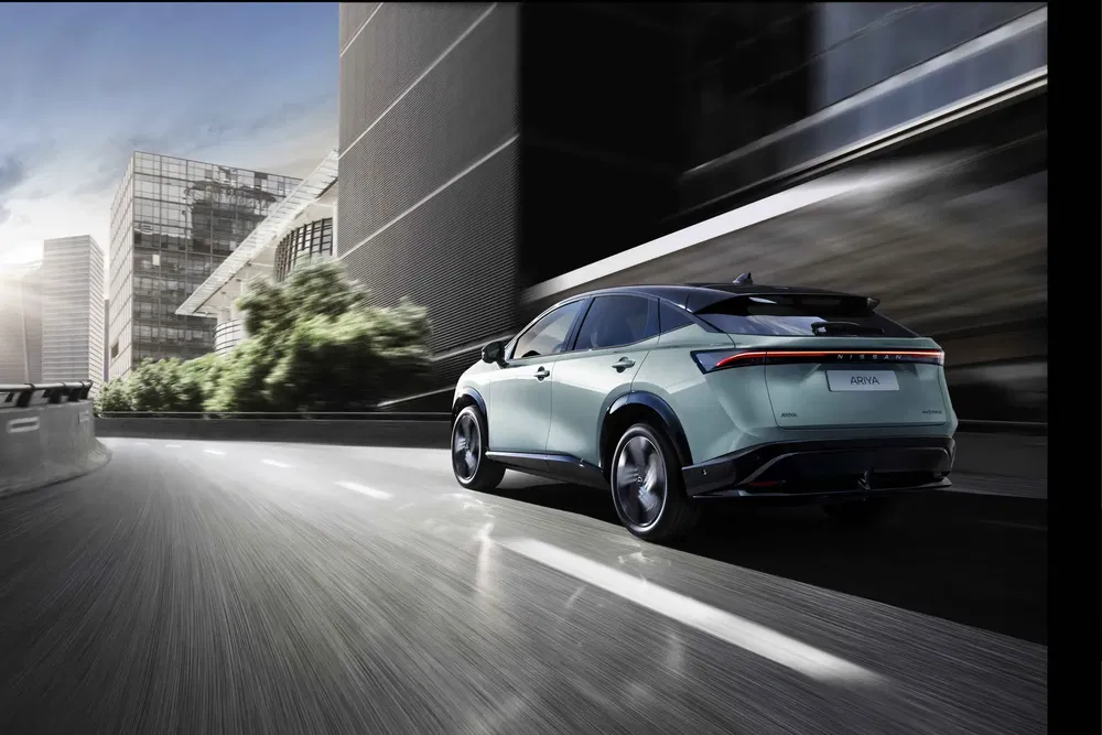 Nissan Ariya électrique roulant en ville moderne, design élégant et futuriste.