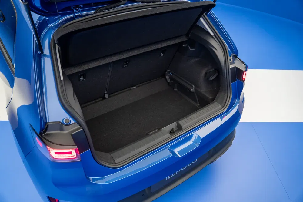 Coffre spacieux de la Volkswagen ID.3 bleu avec hayon ouvert sur fond bleu.