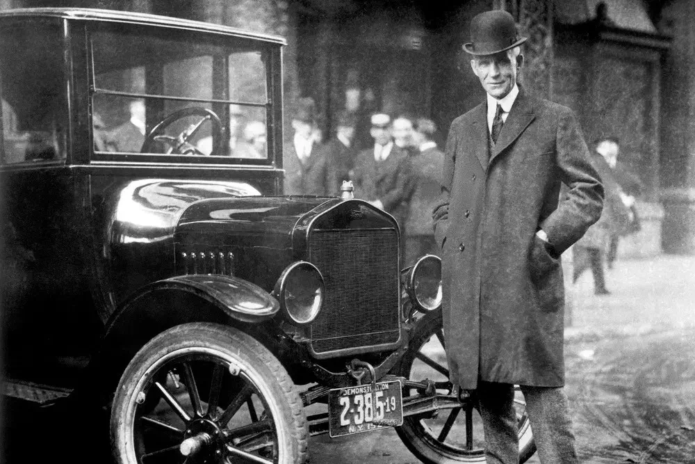 Homme avec Ford Model T vintage devant bâtiment historique.