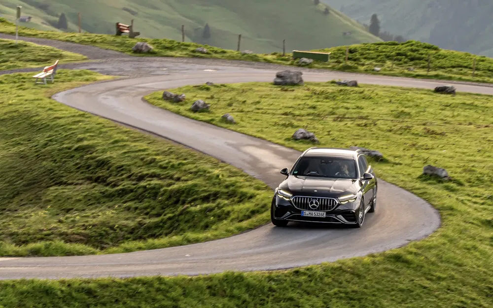Mercedes AMG sur route de montagne sinueuse entourée de paysages verdoyants.