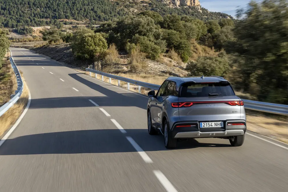 SUV Chery gris sur route sinueuse entourée de collines boisées.