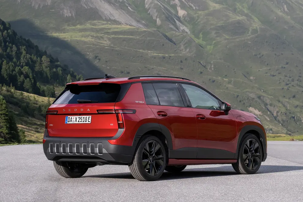 SUV Skoda rouge garé avec montagnes en arrière-plan, design moderne et élégant.