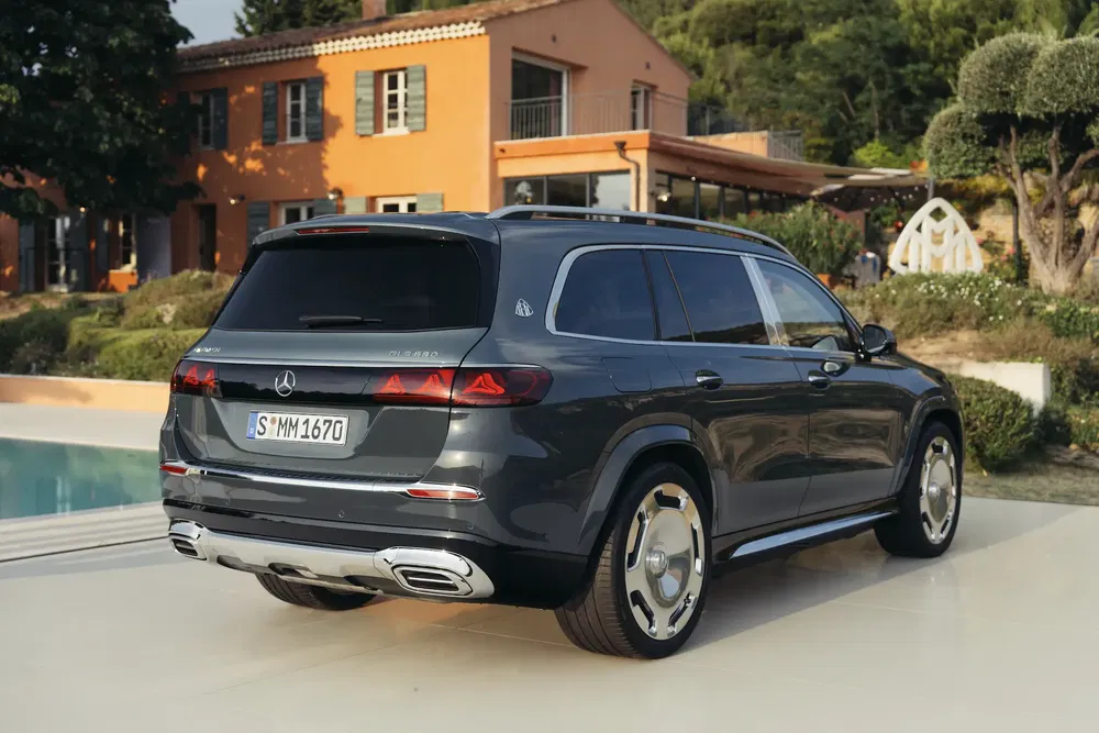 Mercedes-Benz GLS Maybach 2024 garé devant une villa moderne avec piscine, vue arrière latérale.
