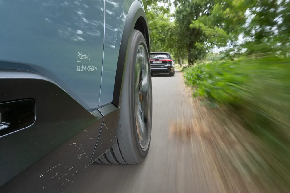 Dynamisch beeld van een Polestar 3 op een landelijke weg met bomen.
