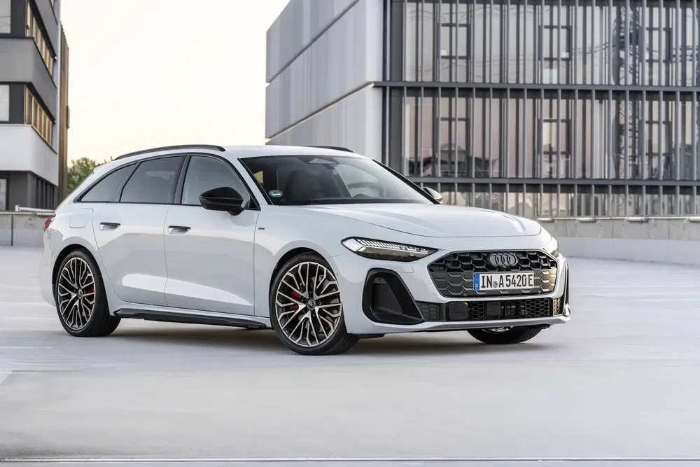 Witte Audi A6 Avant op een dak met moderne architectuur op de achtergrond.
