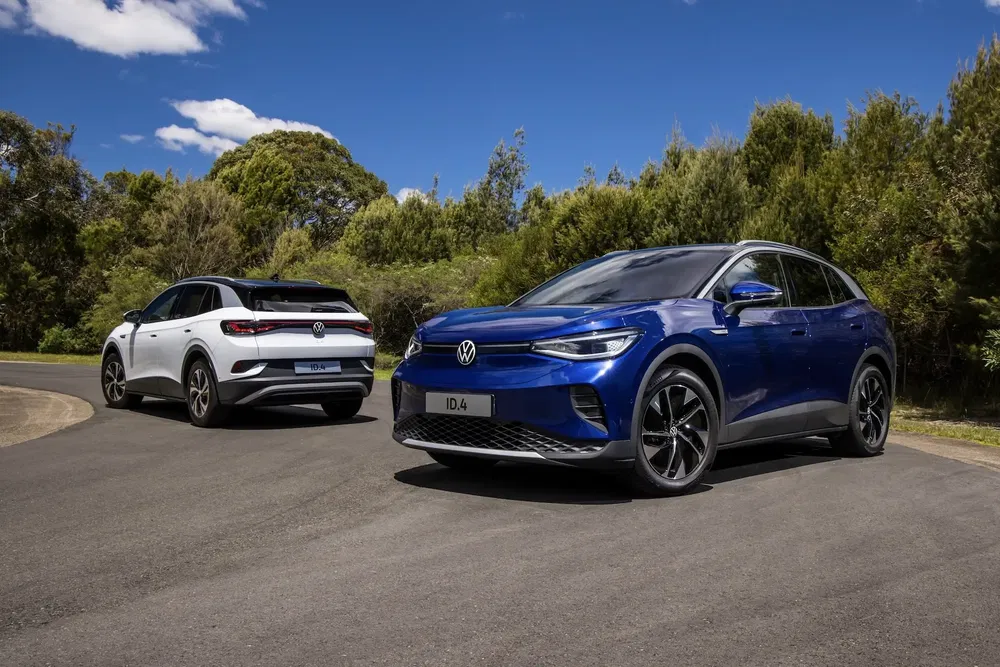 Deux Volkswagen ID.4 électriques stationnées sur une route entourée de végétation et ciel bleu.