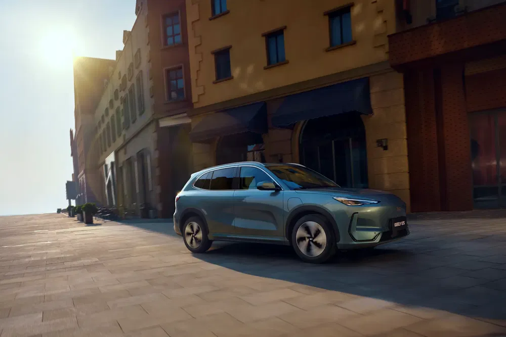 Blauwe elektrische NIO ES6 SUV op een geplaveide straat voor historische gebouwen.