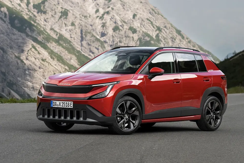 SUV Skoda moderne rouge garé devant des montagnes imposantes.