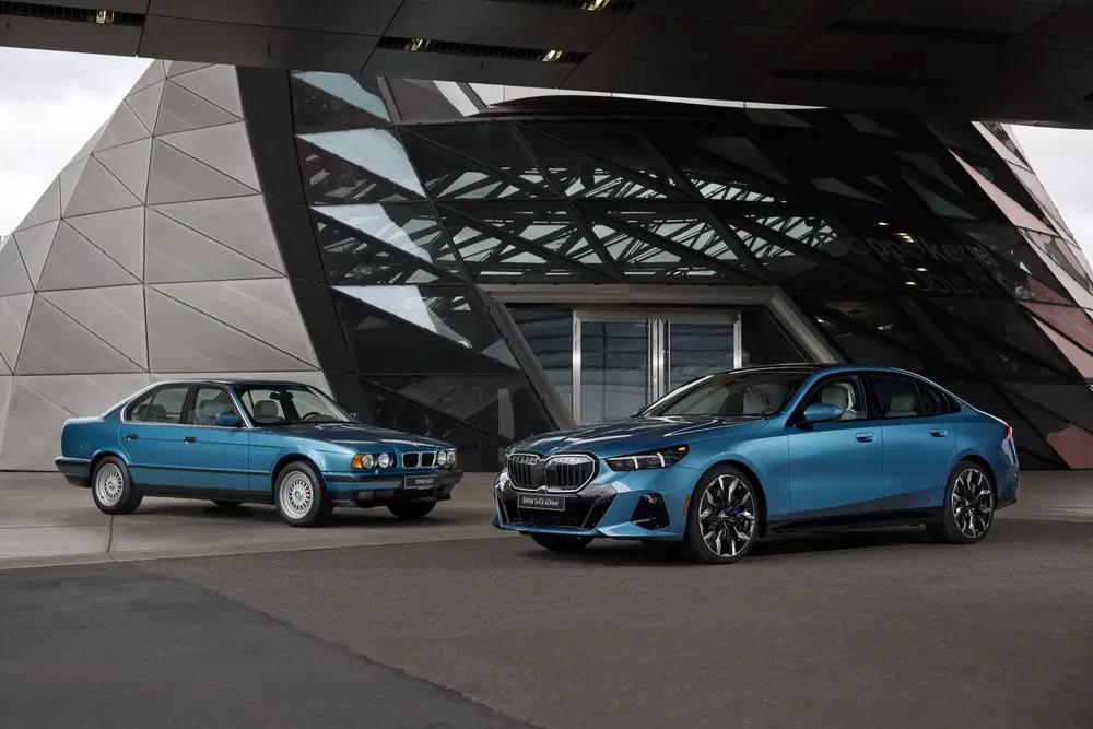 Twee BMW's naast elkaar, klassiek en modern, voor futuristische architectuur.