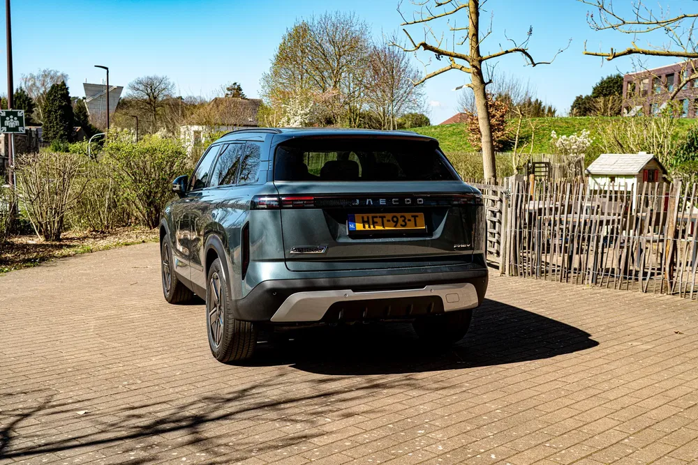 Hybride SUV Jacco geparkeerd op een zonnige oprit met bomen op de achtergrond.