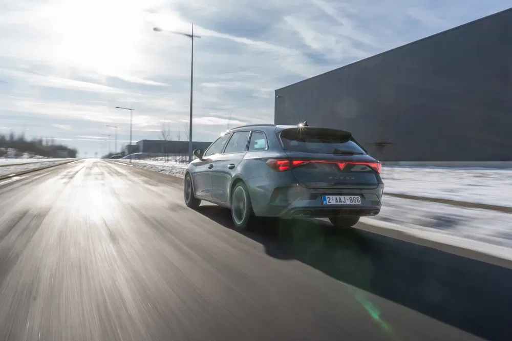 Kia Ceed stationwagen rijdt op besneeuwde weg, industriële winterachtergrond.