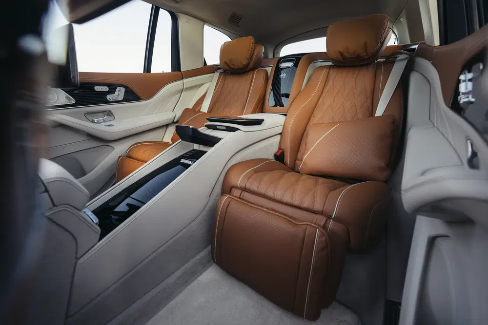 Intérieur luxueux d'une Mercedes-Benz avec sièges en cuir marron et accoudoir central.
