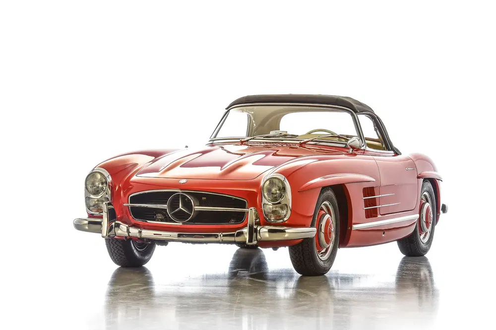 Mercedes-Benz 300SL rouge classique, capote noire, sur fond blanc.