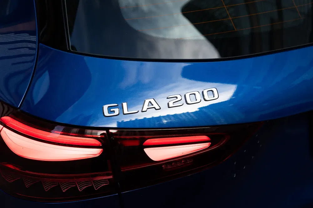 Vue arrière d'une Mercedes GLA 200 bleue avec feux arrière allumés.