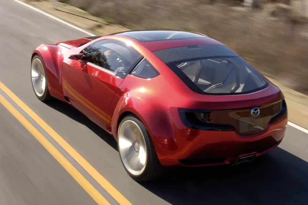 Mazda RX-Vision rouge sur route, montrant son design sportif et aérodynamique.