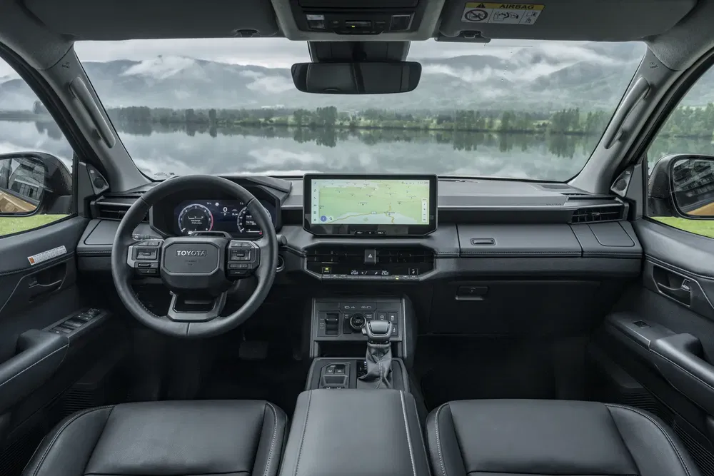 Intérieur spacieux et moderne d'un Toyota Land Cruiser avec écran tactile et vue sur le lac.