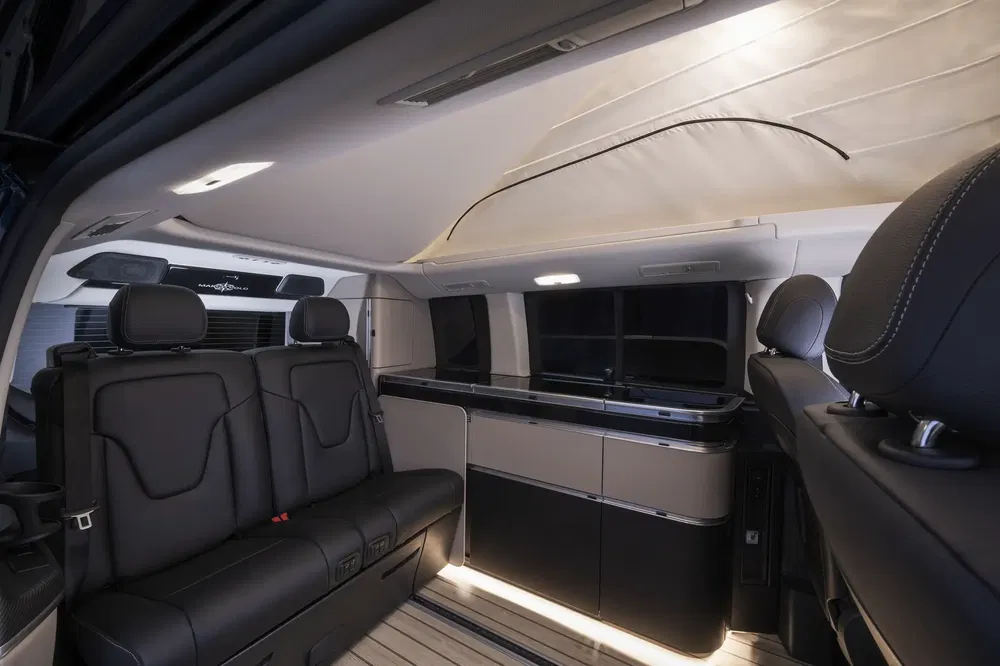 Luxe interieur van camper, lederen stoelen en moderne keukenvoorzieningen.