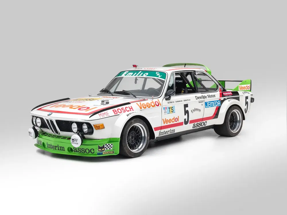{"fr":"Voiture de course BMW classique, modèle CSL, livrée sponsorisée, fond gris.","nl":"Klassieke BMW raceauto, model CSL, sponsorbeplakte livery, grijze achtergrond."}