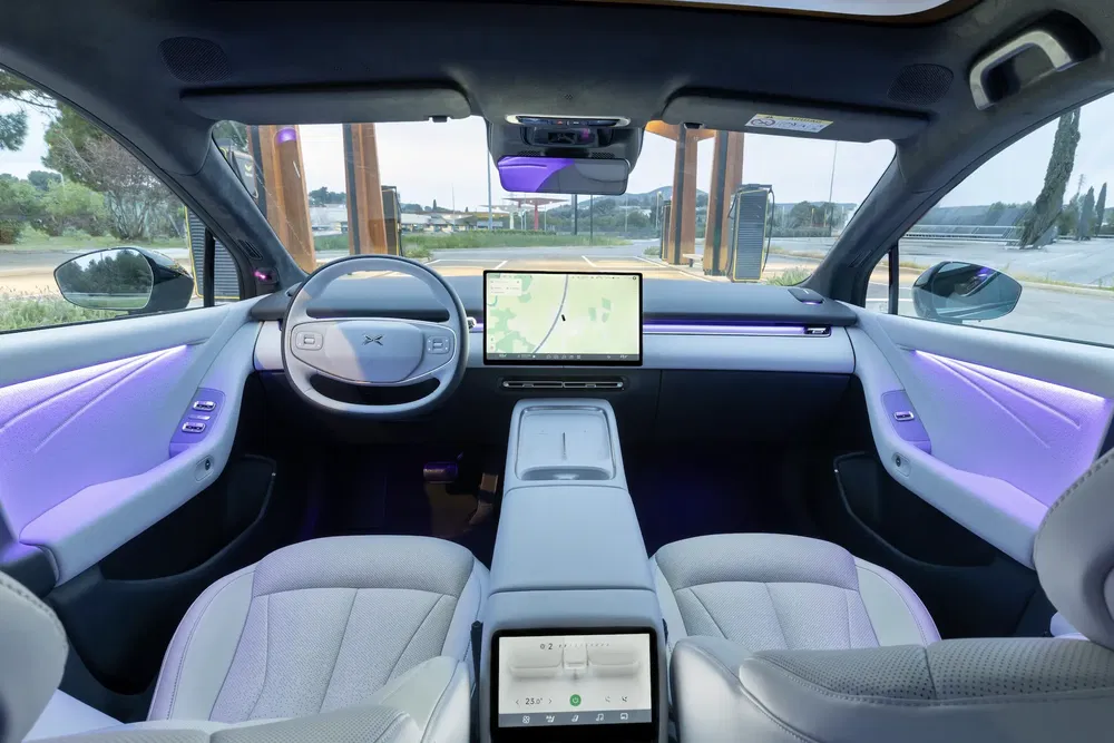 Intérieur moderne d'une voiture électrique Xpeng avec éclairage d'ambiance violet et écran central tactile.