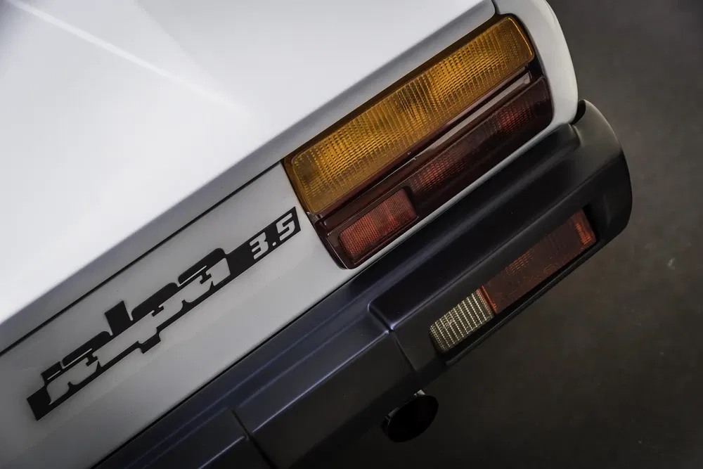 Détail arrière d'une BMW Alpina C2 3.5 avec badge distinctif et feux arrière colorés.