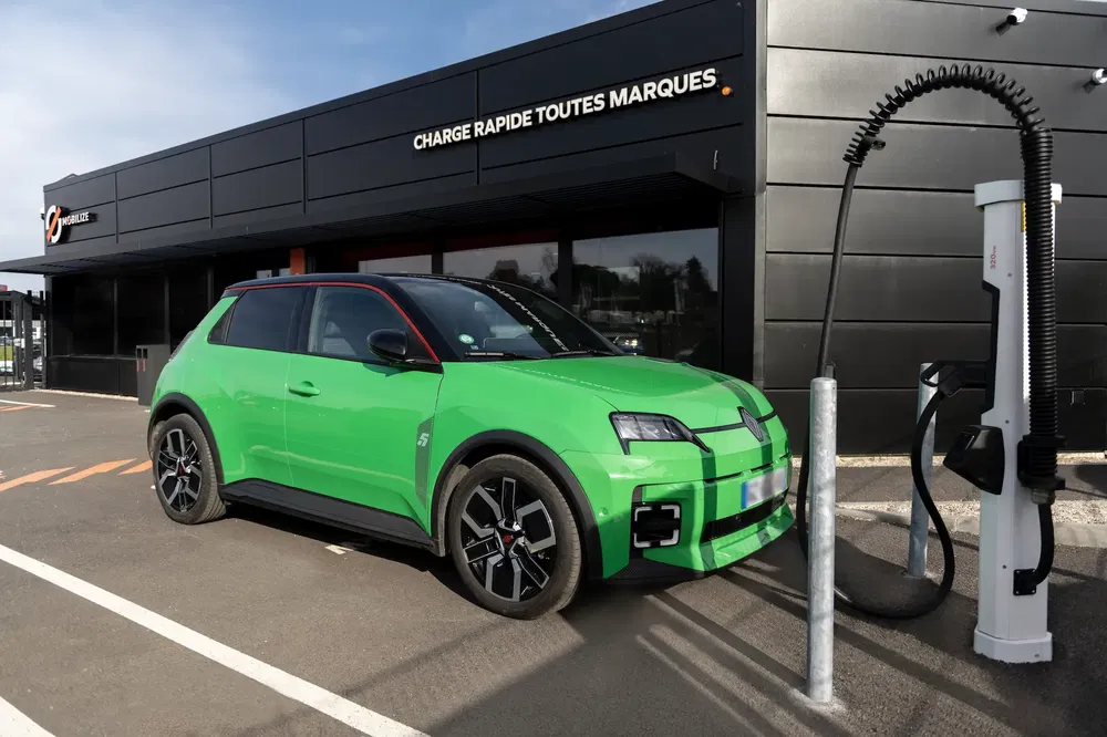 Renault électrique vert vif en charge rapide dans une station moderne en France.