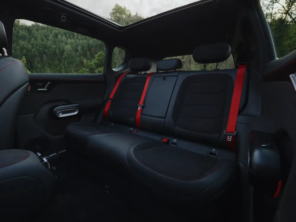 Achterinterieur van een moderne auto met rode gordels en glazen dakhemel.