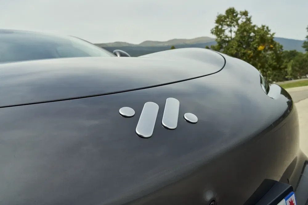 Logo innovant sur capot arrière d'une voiture noire, inscription sur plaque d'immatriculation.