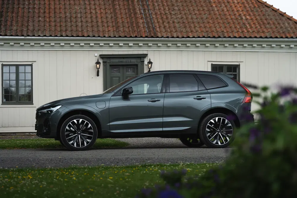 Profil latéral d'un SUV Volvo XC60 gris devant une maison traditionnelle.
