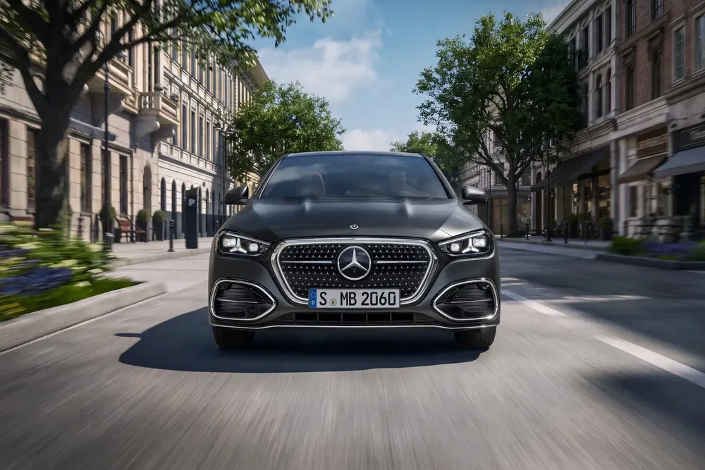 Mercedes-Benz Classe S circulant dans une rue bordée d'arbres et de bâtiments élégants.