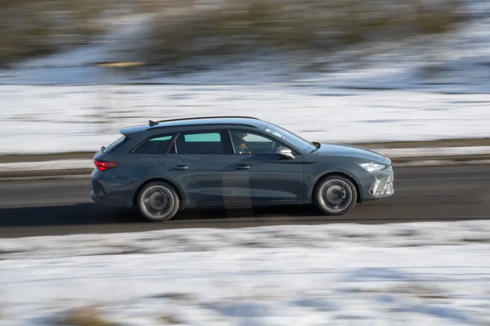 Stationwagen rijdt snel op besneeuwde weg, onscherpe achtergrond.
