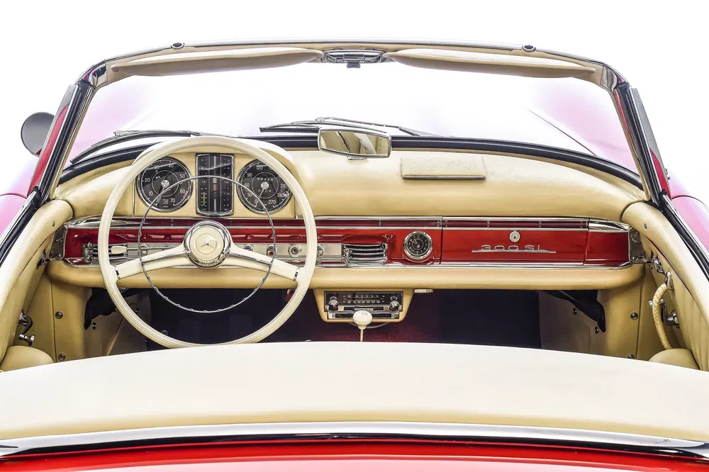 Tableau de bord d'une Mercedes-Benz 300SL classique, intérieur cuir beige et rouge vibrant.