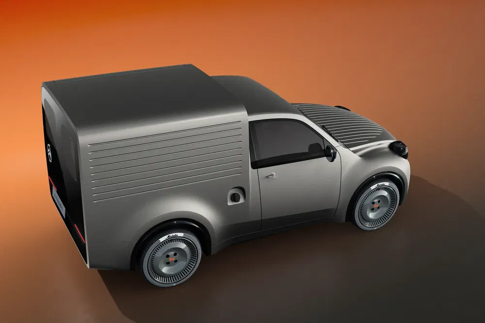 Concept-car utilitaire futuriste à carrosserie argentée et roues spécifiques sur fond orange.