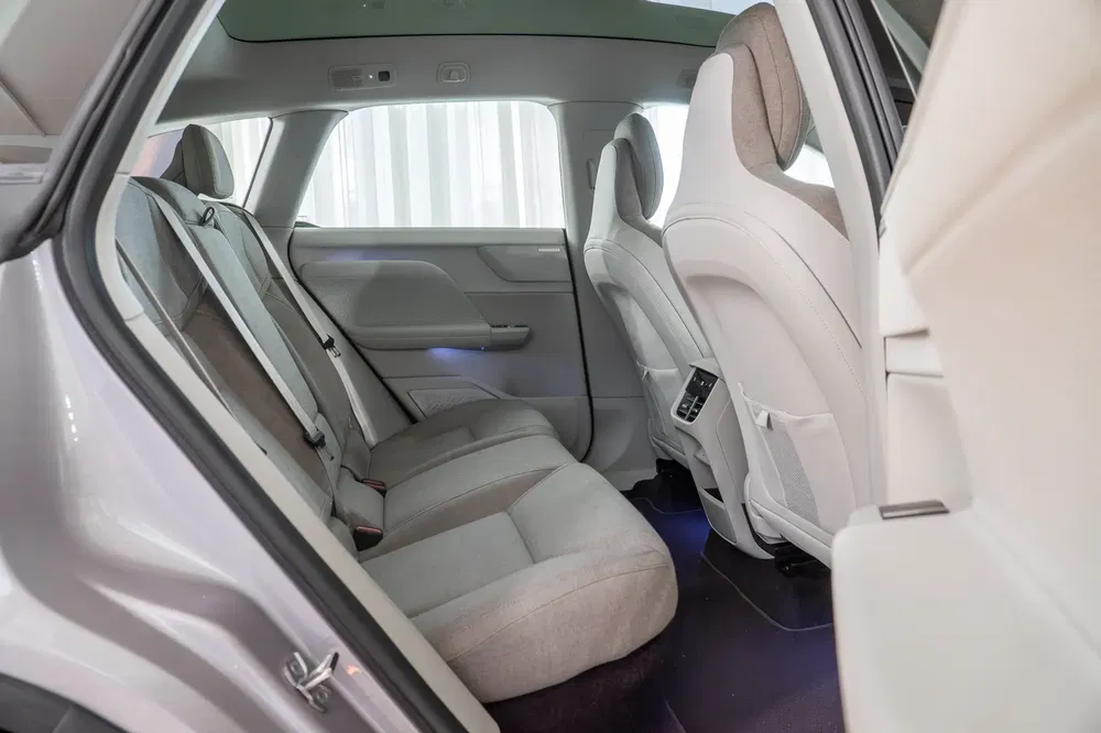 Intérieur spacieux d'une voiture électrique moderne avec sièges arrière en tissu et éclairage délicat.