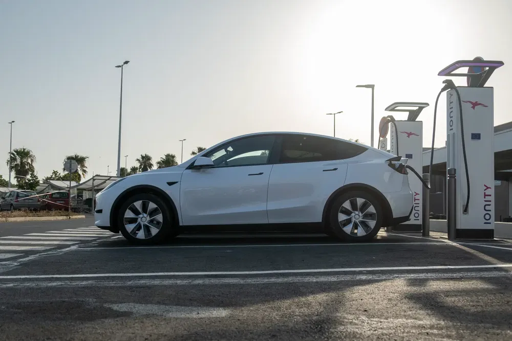 Tesla Model Y blanche en charge à une borne Ionity sous un ciel clair.