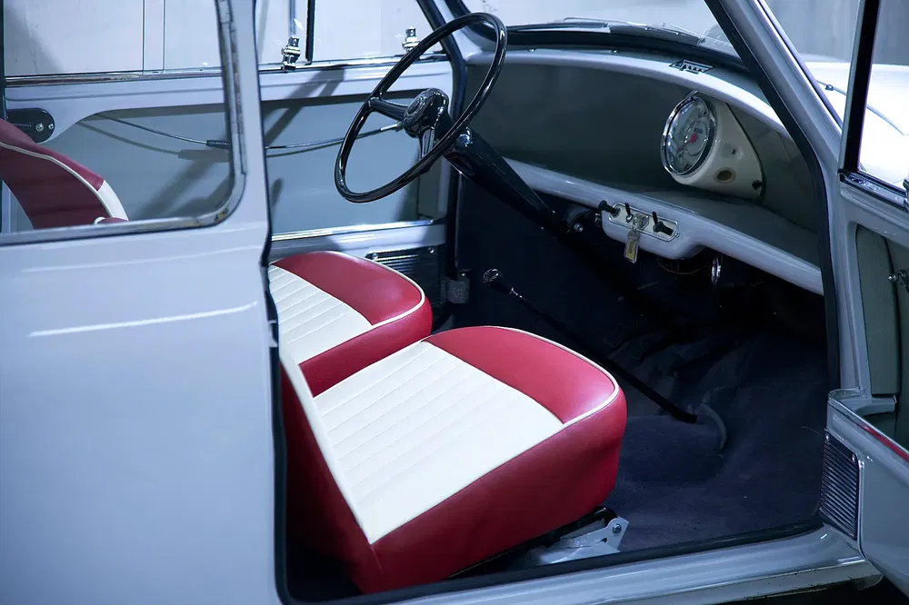 Stijlvol interieur van klassieke auto met rood-witte stoelen en vintage stuur.