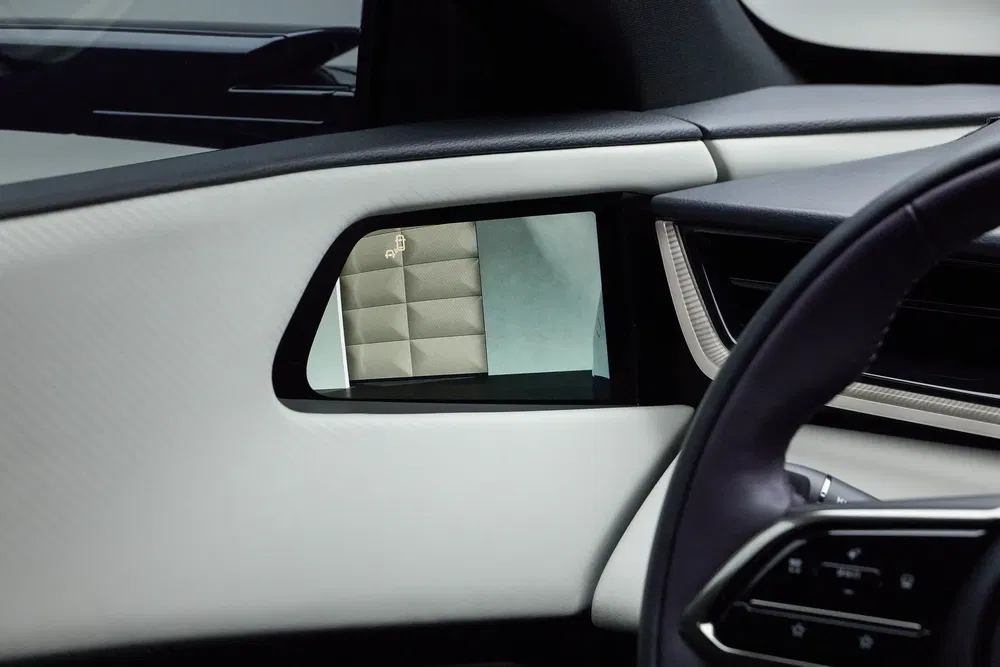 Intérieur d'une voiture BMW i7 avec caméra latérale et écran d'affichage numérique moderne.