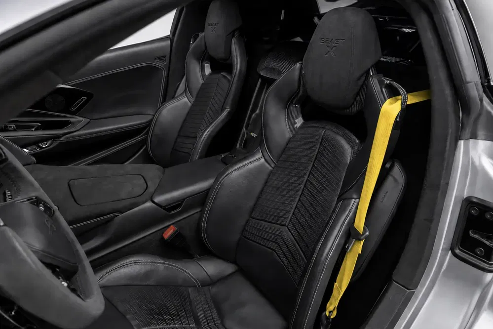 Koenigsegg Regera interieur met zwarte lederen stoelen en gele veiligheidsgordel.