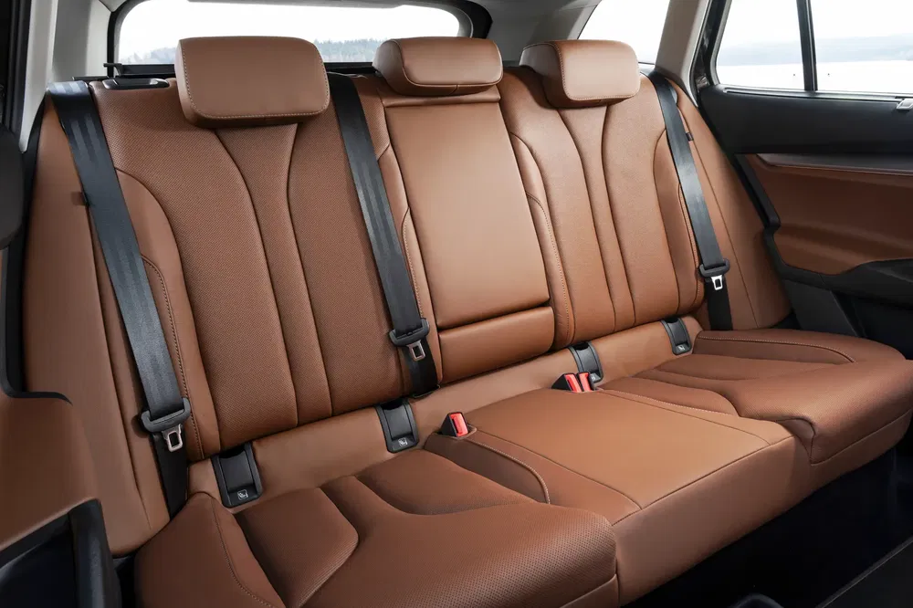 Intérieur en cuir brun d'un SUV moderne avec sièges arrière spacieux et ceintures de sécurité.