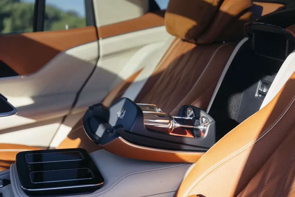 Intérieur luxueux d'une voiture Maybach avec sièges en cuir marron et accoudoir central évoquant l'élégance.