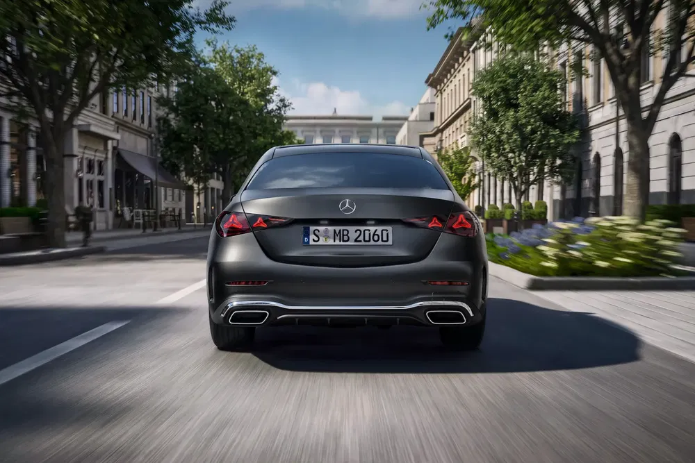 Mercedes-Benz Classe S noire roulant en ville bordée d'arbres.