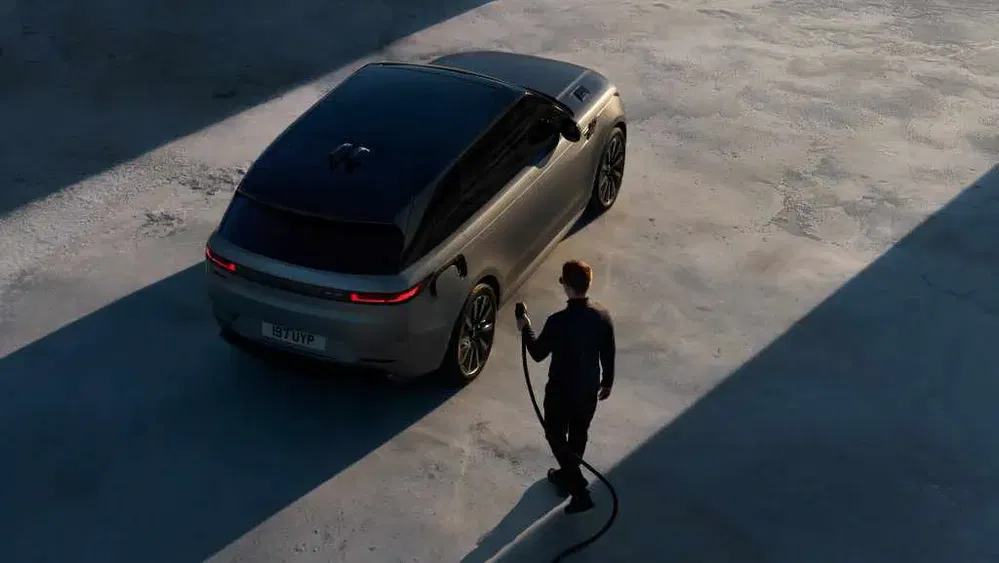 Range Rover gris en charge, éclairage de soirée sur parking.