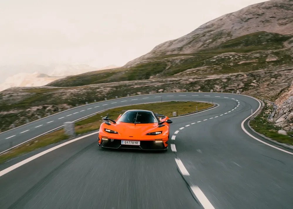 Oranje supercar op kronkelende bergweg, indrukwekkende prestatie en snelheid.